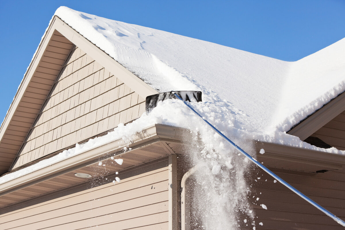 a roof rake being used to remove snow from the roof of a house