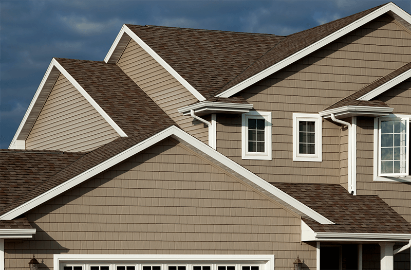 Residential home with complex roof sections covered with brown, textured asphalt shingles.